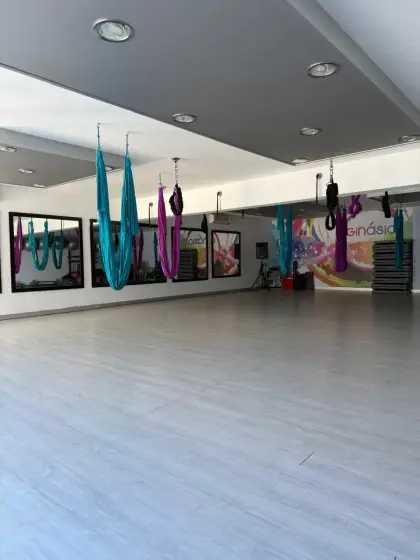 O Estúdio 2, amplo e vazio, com os tecidos de Aereo Yoga suspensos do tecto, espelhos e o mural colorido ao fundo.